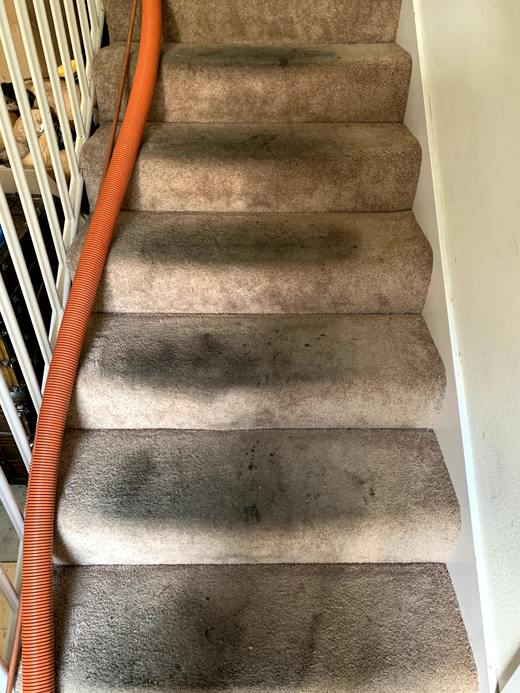 Carpeted staircase before cleaning, soiled and dull